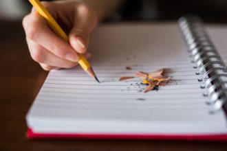 Dłoń ucznia trzymającego ołówek